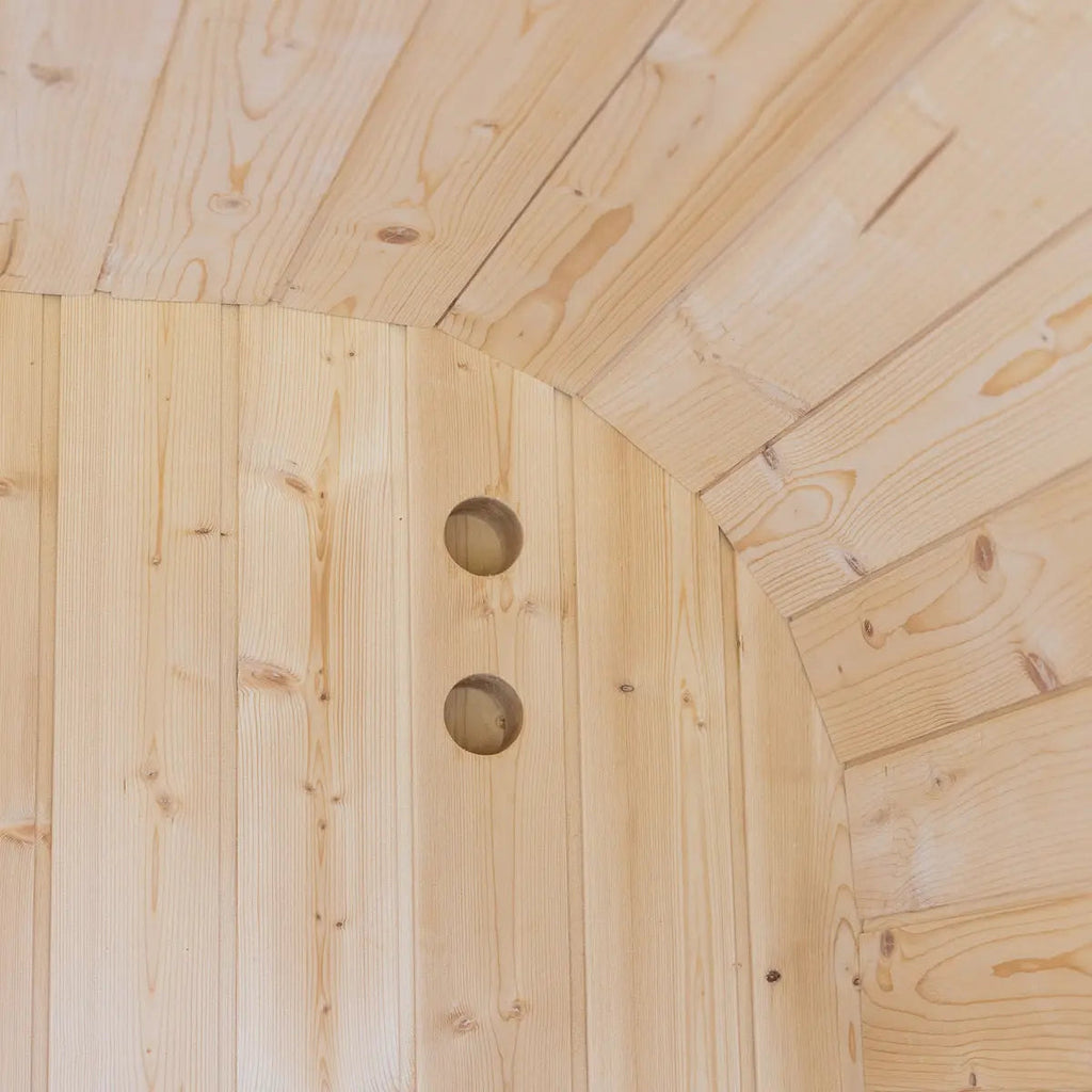 Curved cedar paneling inside the Auris One outdoor cedar sauna with rounded vent openings.