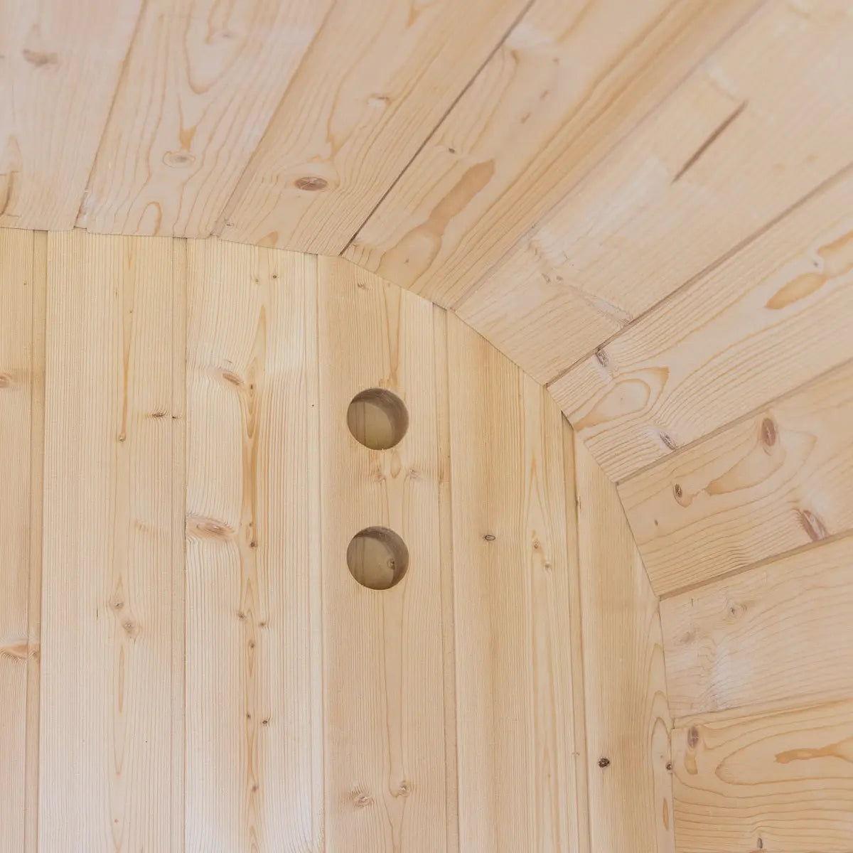 Curved cedar paneling inside the Auris One outdoor cedar sauna with rounded vent openings.