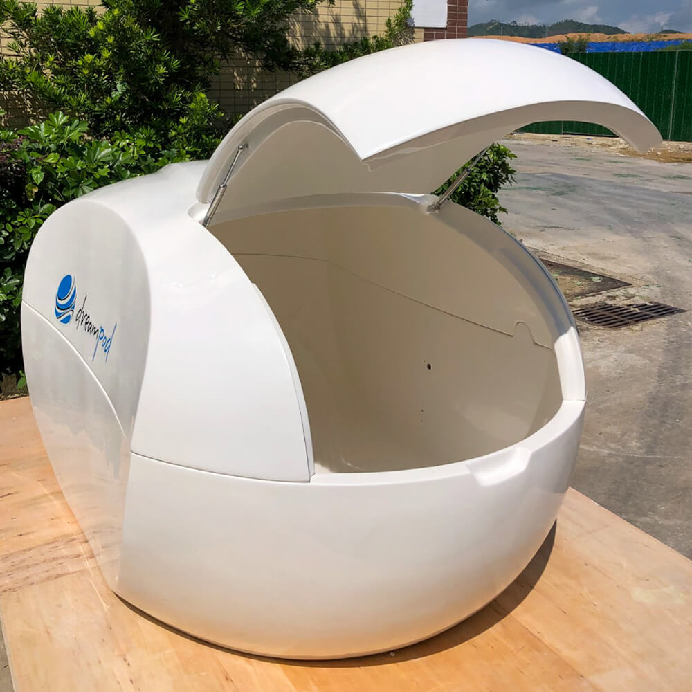 Dreampod Home Float Plus flotation tank shown outdoors from the front right with the door open on a wooden platform
