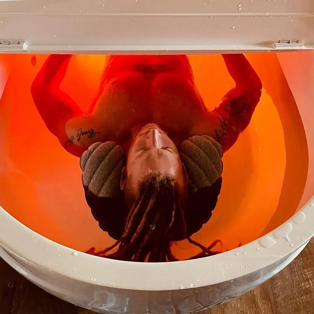 Top view of a person floating inside the Dreampod Home Float Pro with calming orange LED lighting