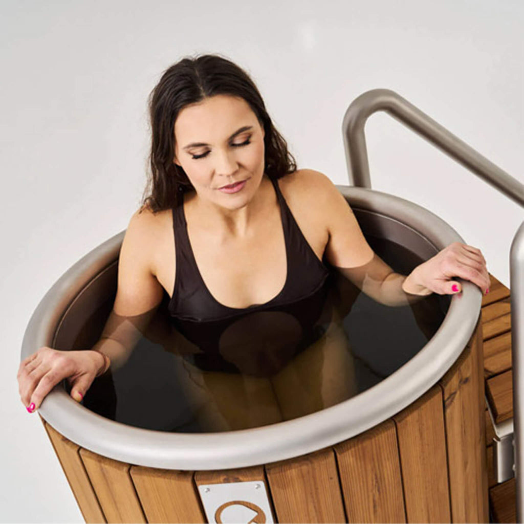Woman using the Icetubs IceBarrel thermowood cold plunge tub with optional handrail system.