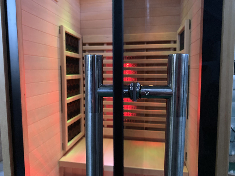 Interior bench seating inside the Lumin One infrared sauna with warm red light and natural wood finish.